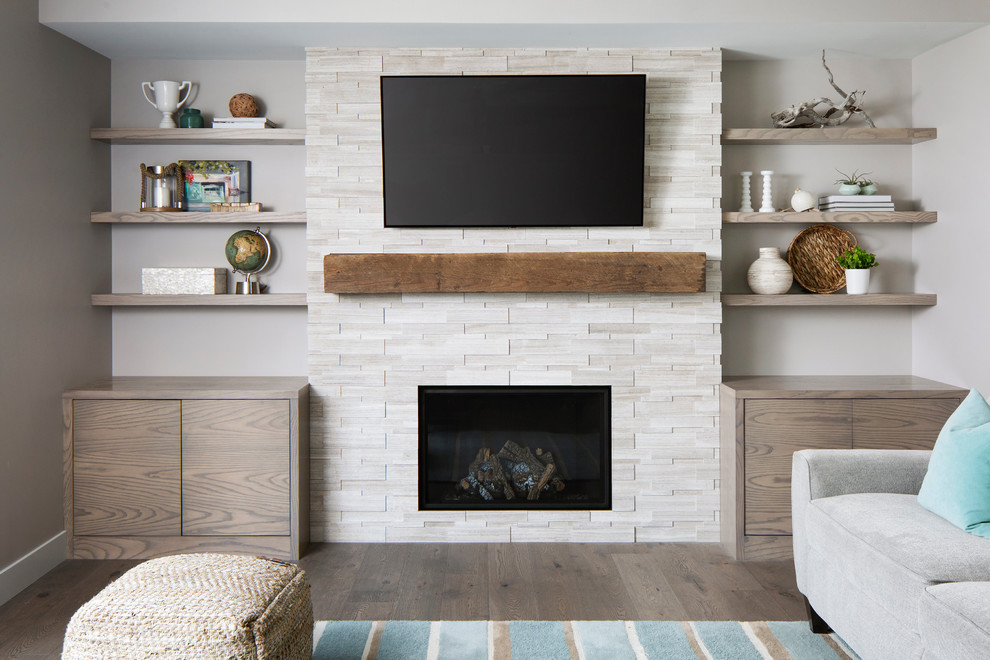 Example of a mid-sized transitional enclosed medium tone wood floor and brown floor family room design in Calgary with gray walls, a standard fireplace, a stone fireplace and a wall-mounted tv