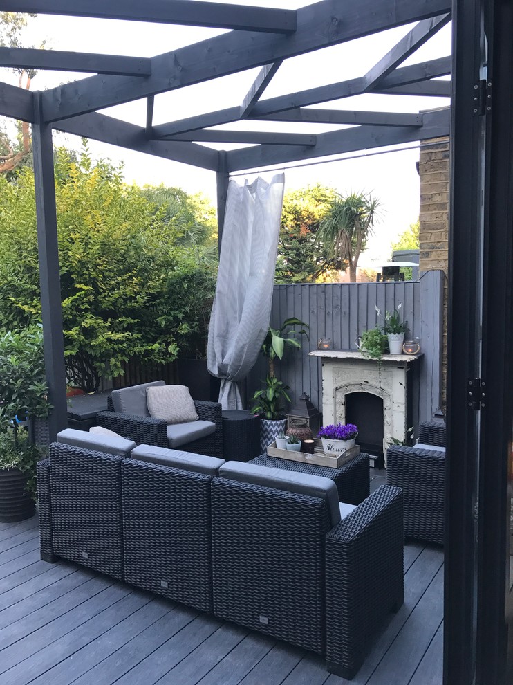 Inspiration for a small traditional backyard patio in London with decking and a pergola.