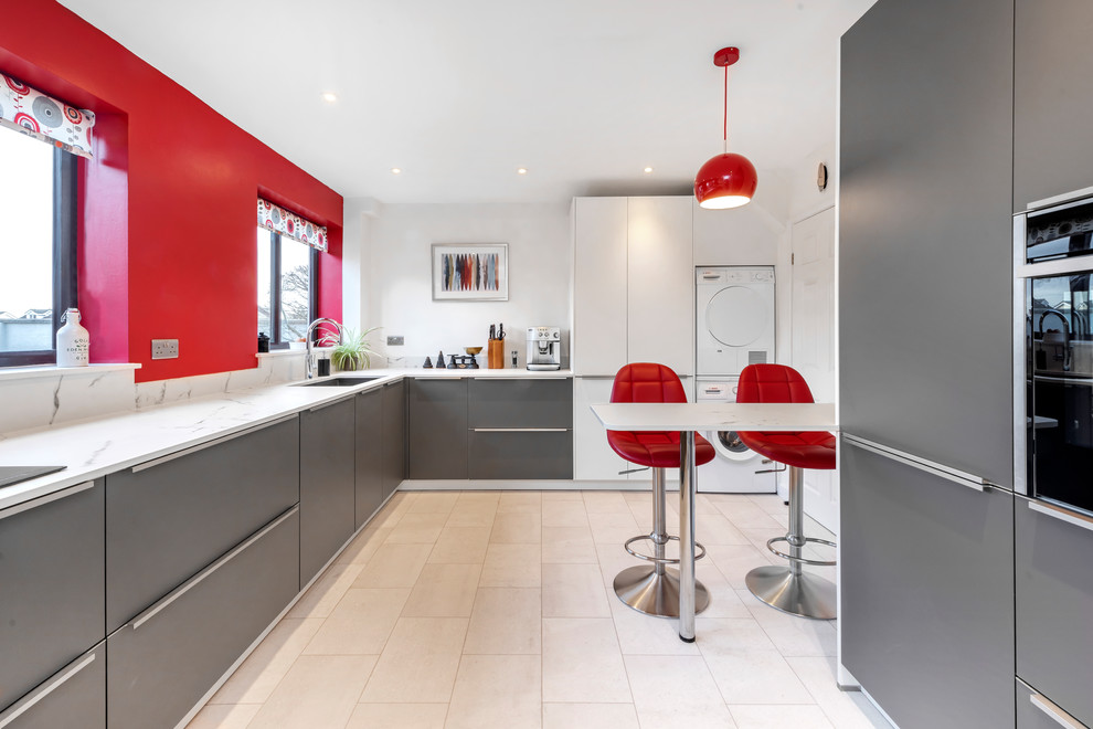 Photo of a mid-sized contemporary l-shaped kitchen in Other with a drop-in sink, red splashback, glass sheet splashback and a peninsula.