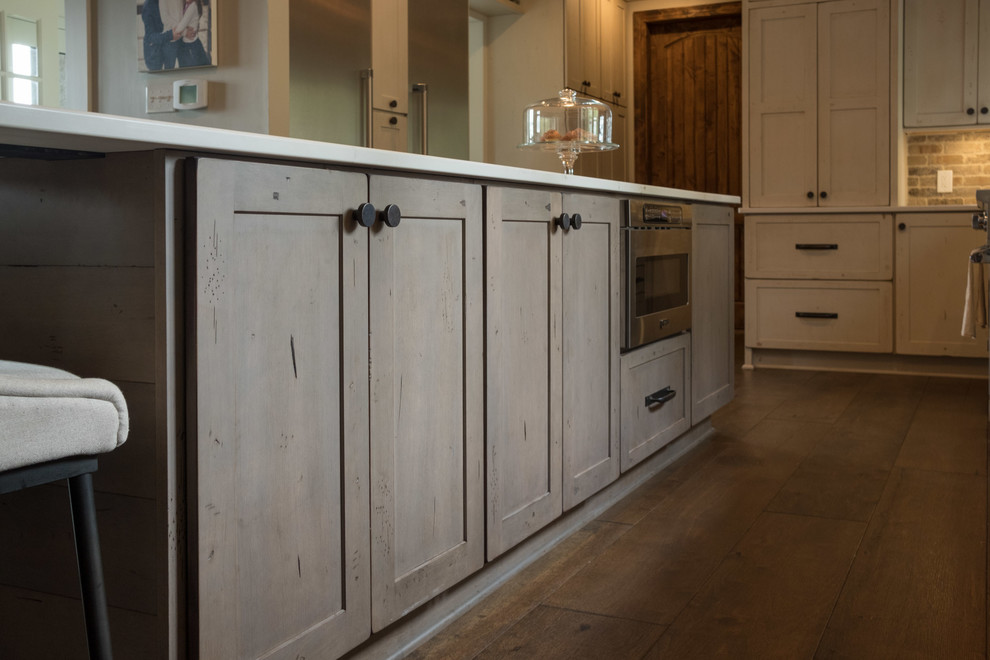 Example of a large transitional galley dark wood floor and brown floor open concept kitchen design with a farmhouse sink, shaker cabinets, quartz countertops, brown backsplash, brick backsplash, stainless steel appliances and an island