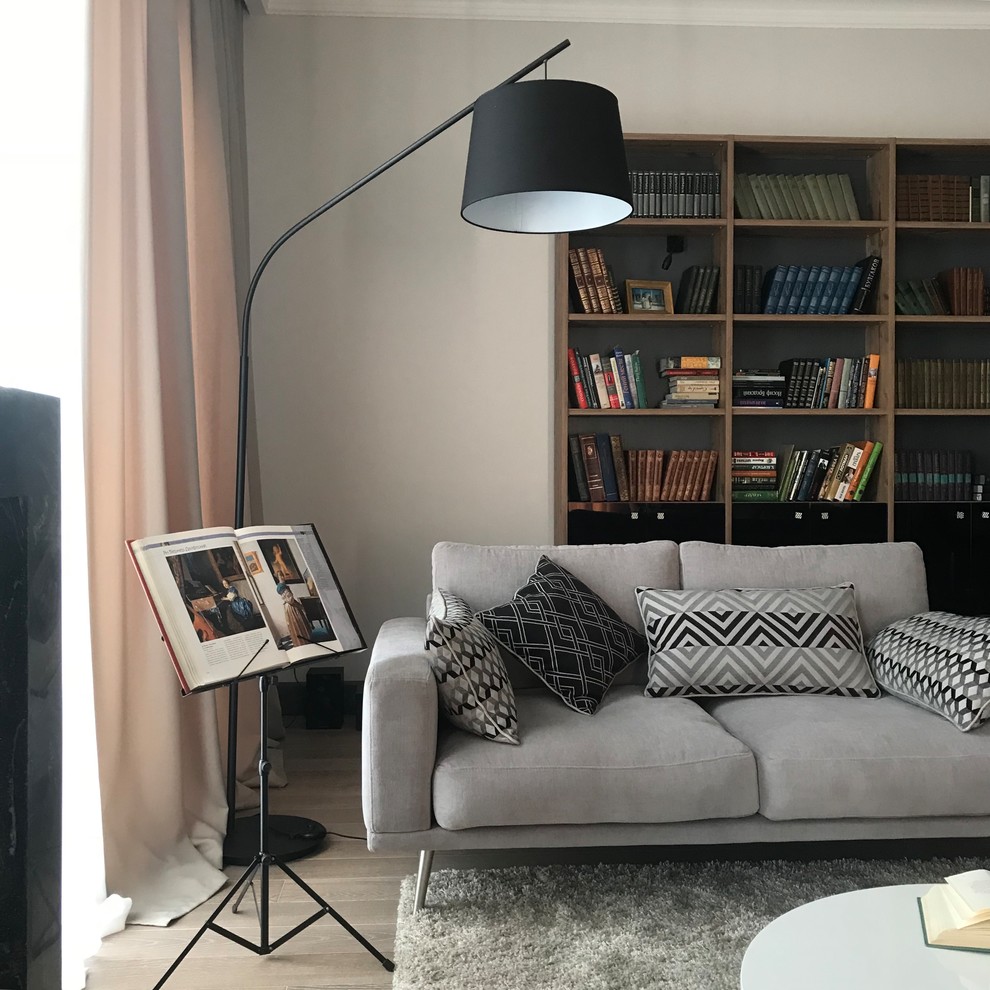 Photo of a contemporary living room in Moscow with a library, grey walls, medium hardwood floors, a standard fireplace, a stone fireplace surround, a wall-mounted tv and beige floor.