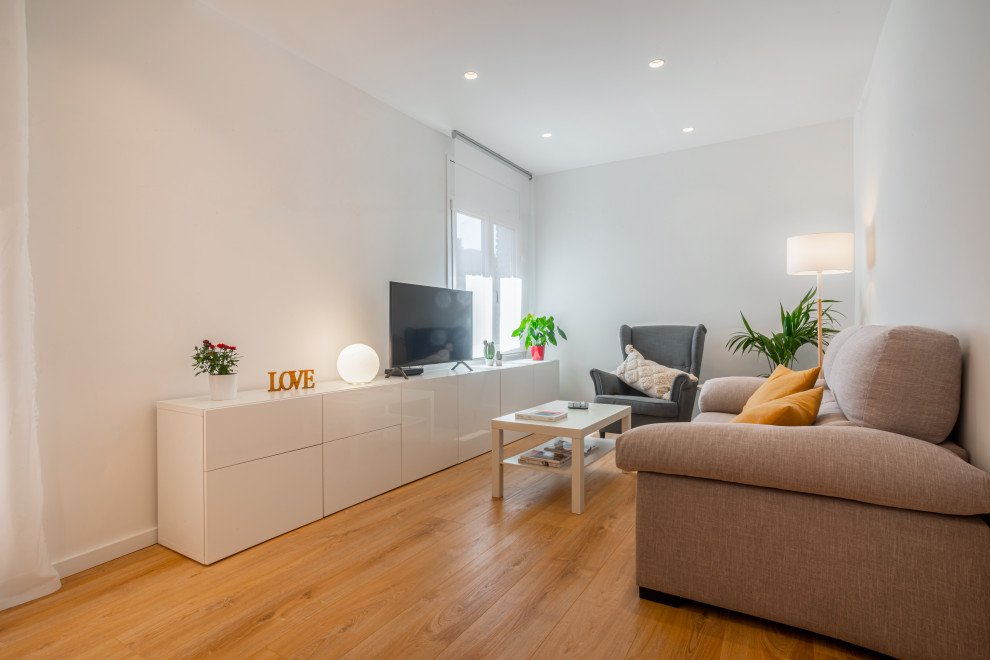 Mittelgroßes, Abgetrenntes Skandinavisches Wohnzimmer mit weißer Wandfarbe, braunem Holzboden und freistehendem TV in Barcelona