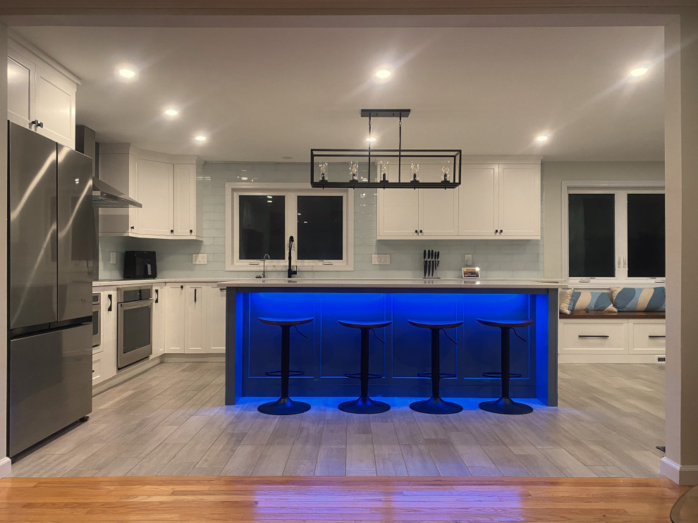 Exemple d'une très grande cuisine ouverte tendance en L avec un évier encastré, un placard à porte shaker, des portes de placard blanches, un plan de travail en quartz modifié, une crédence blanche, une crédence en carrelage métro, un sol en carrelage de porcelaine, îlot, un sol gris et un plan de travail blanc.