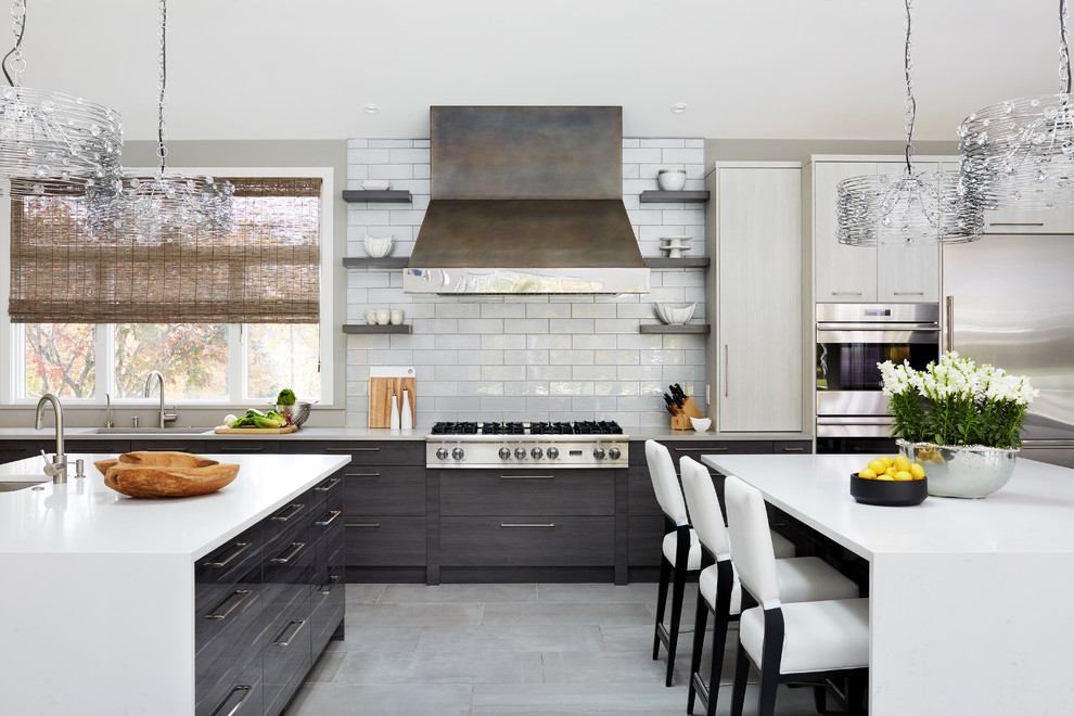 This is an example of a contemporary eat-in kitchen in DC Metro with an undermount sink, flat-panel cabinets, grey cabinets, white splashback, stainless steel appliances, multiple islands and grey floor.