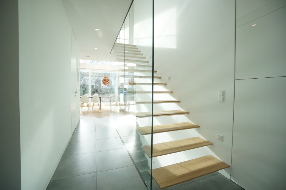 Пример оригинального дизайна: прямая лестница среднего размера в стиле модернизм с деревянными ступенями и стеклянными перилами