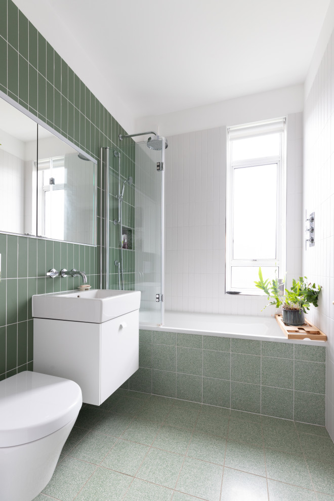 Design ideas for a medium sized contemporary family bathroom in London with flat-panel cabinets, white cabinets, green tiles, green walls, a wall-mounted sink, green floors, a single sink and a floating vanity unit.