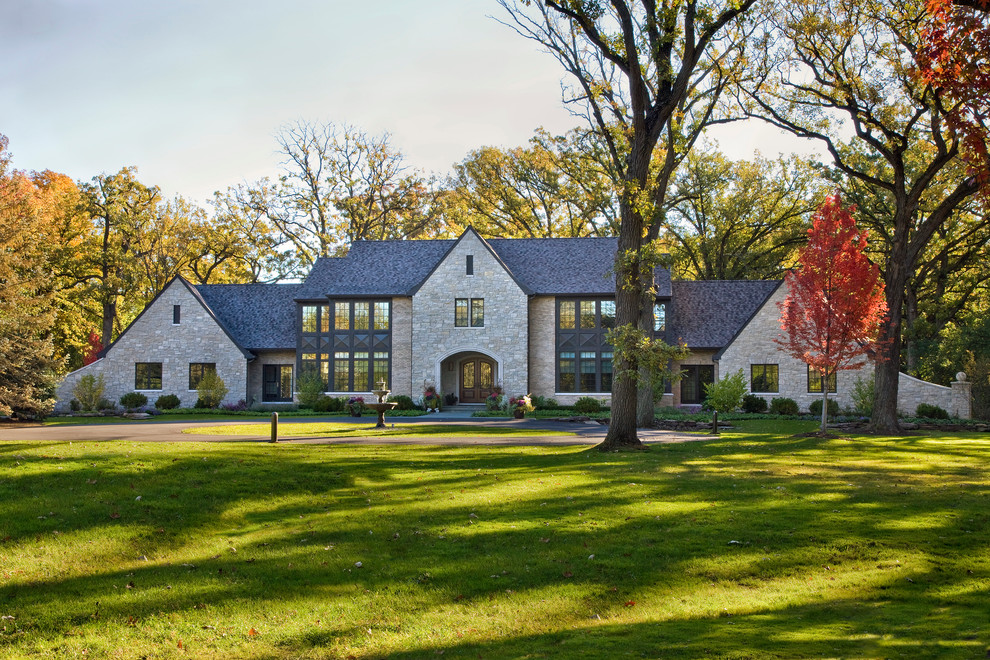 Expansive traditional two-storey beige house exterior in Chicago with stone veneer, a gable roof and a shingle roof.