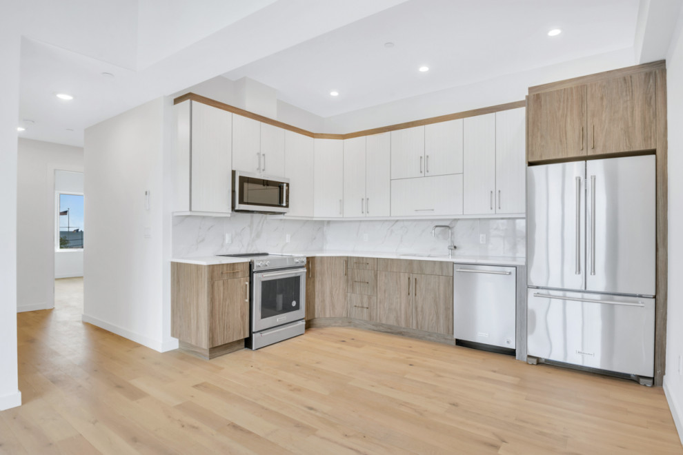 Design ideas for a large modern l-shaped eat-in kitchen in New York with an undermount sink, flat-panel cabinets, distressed cabinets, marble benchtops, grey splashback, marble splashback, stainless steel appliances, plywood floors, brown floor and grey benchtop.