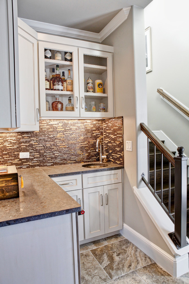 Small transitional l-shaped wet bar in Austin with white cabinets, an undermount sink, recessed-panel cabinets, quartz benchtops, multi-coloured splashback, matchstick tile splashback, porcelain floors and brown floor.