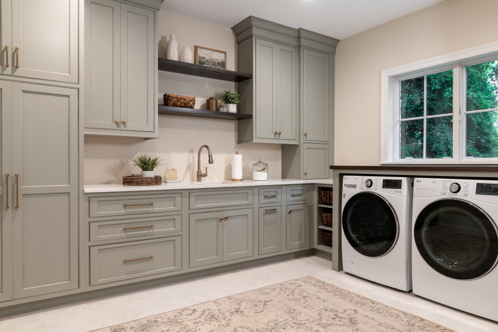 Large transitional dedicated laundry room in St Louis with an undermount sink, beaded inset cabinets, grey cabinets, quartz benchtops, beige walls, porcelain floors, a side-by-side washer and dryer, white floor and white benchtop.