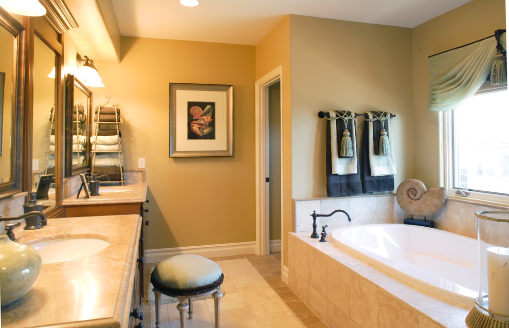 Large beach style master bathroom in Orange County with a drop-in tub, a one-piece toilet, beige tile, ceramic tile, beige walls, ceramic floors, beige floor, raised-panel cabinets, medium wood cabinets, an undermount sink and limestone benchtops.