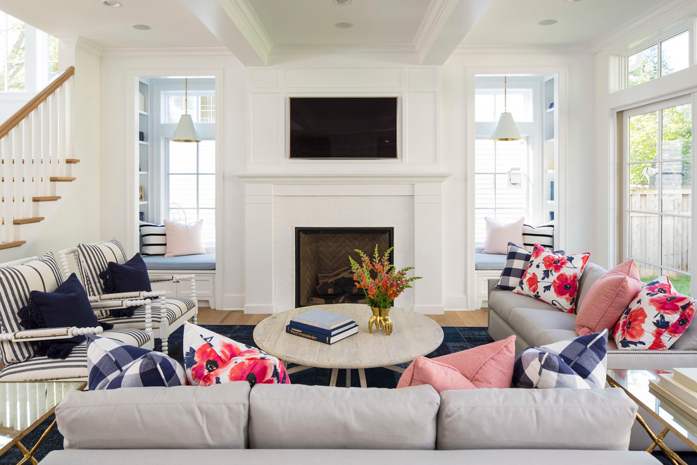 Inspiration for a large beach style open concept family room in Minneapolis with white walls, light hardwood floors, a standard fireplace, a wall-mounted tv, a wood fireplace surround and brown floor.