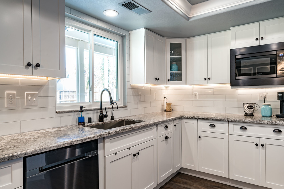 Inspiration for a mid-sized transitional u-shaped dark wood floor and brown floor eat-in kitchen remodel with an undermount sink, shaker cabinets, white cabinets, granite countertops, white backsplash, subway tile backsplash, stainless steel appliances and an island