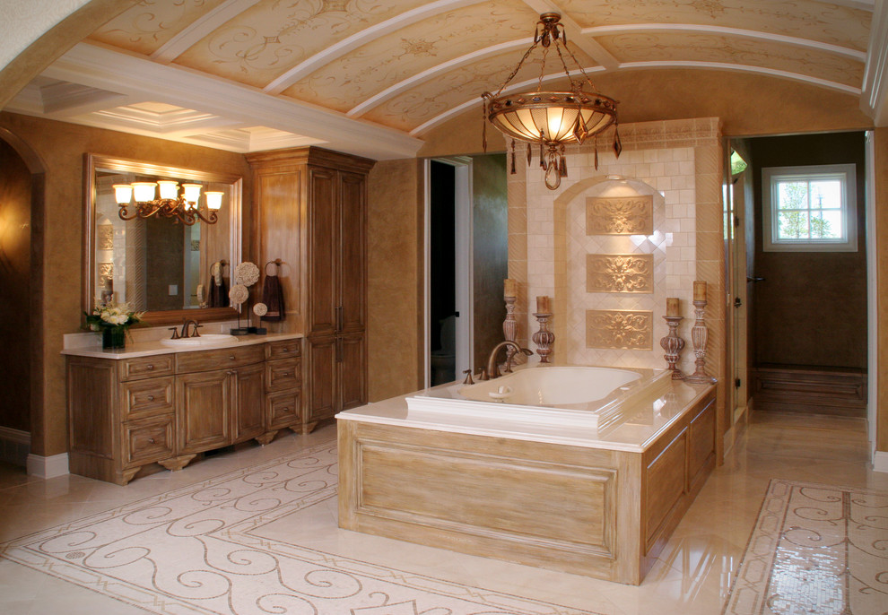 Design ideas for a mediterranean bathroom in Cleveland with a drop-in sink, distressed cabinets, a drop-in tub, beige tile and raised-panel cabinets.