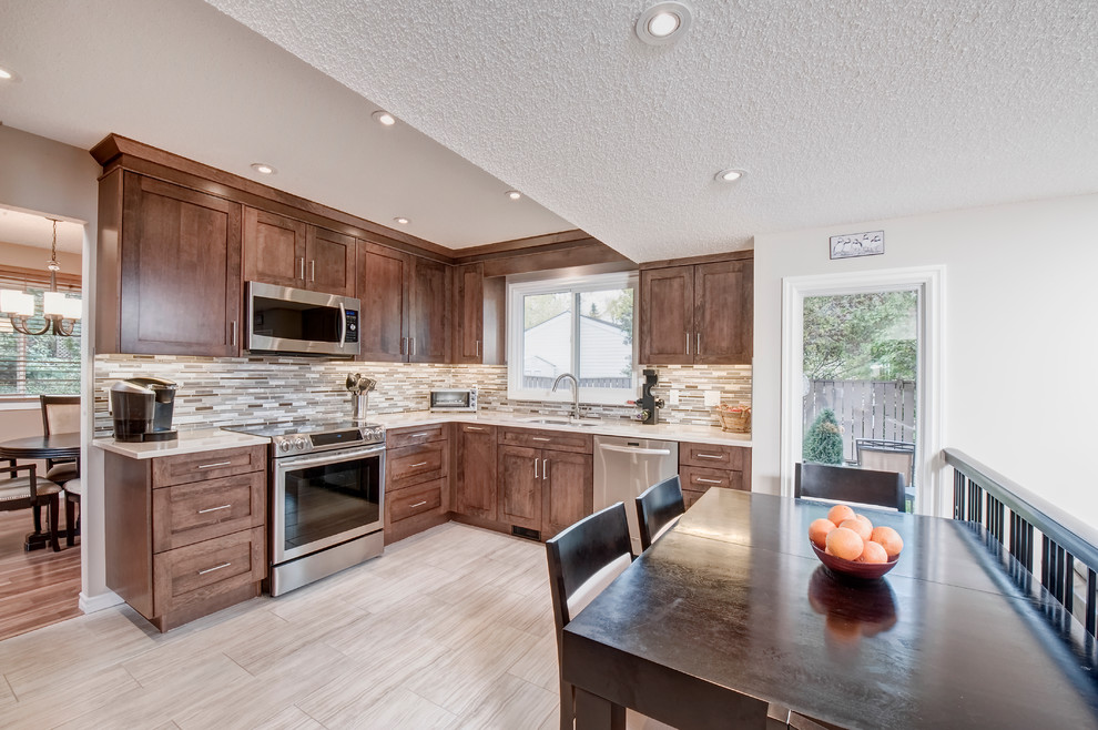 Eat-in kitchen - mid-sized transitional l-shaped porcelain tile and beige floor eat-in kitchen idea in Calgary with an undermount sink, shaker cabinets, medium tone wood cabinets, quartz countertops, multicolored backsplash, mosaic tile backsplash, stainless steel appliances and no island