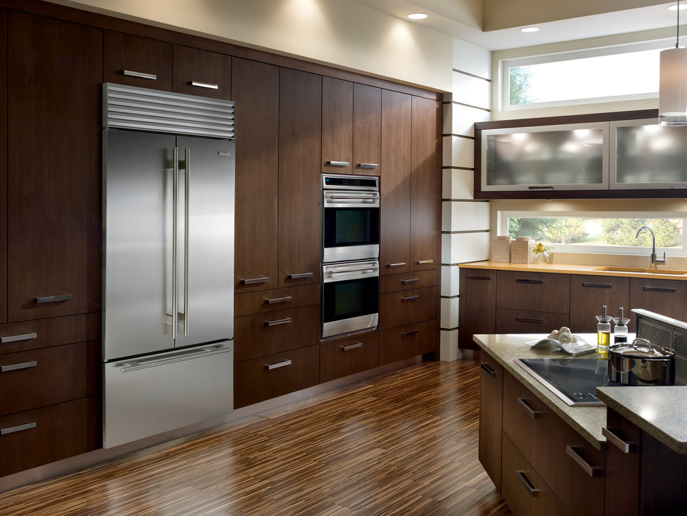 This is an example of a traditional separate kitchen in Philadelphia with flat-panel cabinets, dark wood cabinets, granite benchtops, stainless steel appliances, with island and brown floor.