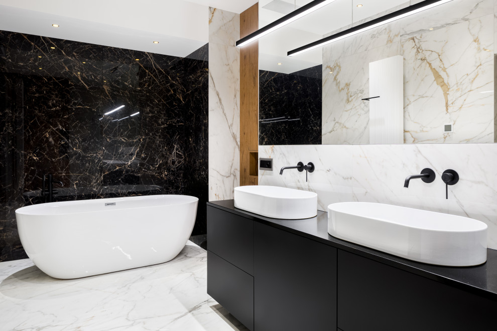Inspiration for a mid-sized contemporary bathroom in Tampa with flat-panel cabinets, black cabinets, a freestanding tub, black and white tile, marble, white walls, marble floors, a vessel sink, white floor, a niche, a double vanity, a built-in vanity and wood walls.