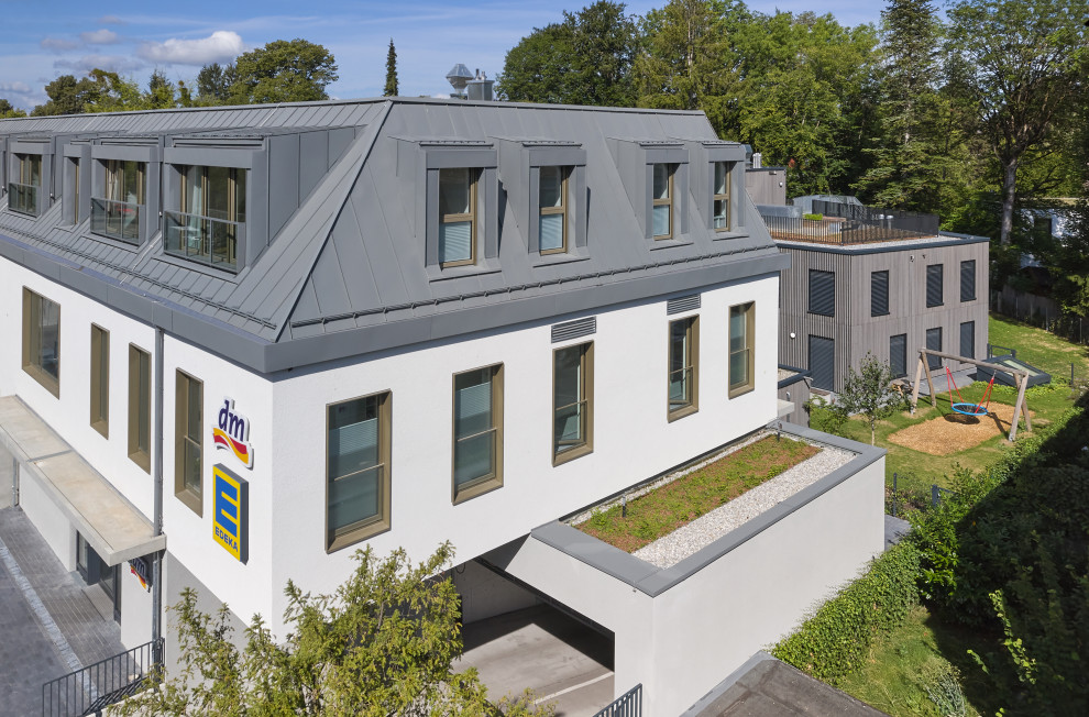 Mittelgroßes, Dreistöckiges Modernes Haus mit Putzfassade, weißer Fassadenfarbe, Halbwalmdach, grauem Dach und Dachgaube in München