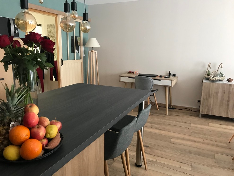 This is an example of a mid-sized scandinavian l-shaped open plan kitchen in Strasbourg with an undermount sink, light wood cabinets, laminate benchtops, grey splashback, light hardwood floors, with island and grey benchtop.