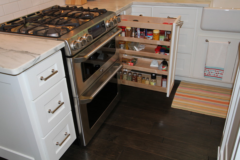 Eat-in kitchen - transitional dark wood floor eat-in kitchen idea with a farmhouse sink, recessed-panel cabinets, white cabinets, marble countertops, white backsplash, subway tile backsplash, stainless steel appliances and an island