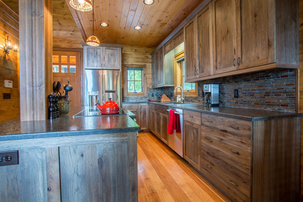Example of a mid-sized mountain style l-shaped medium tone wood floor and brown floor eat-in kitchen design in Charlotte with an undermount sink, shaker cabinets, dark wood cabinets, granite countertops, multicolored backsplash, glass tile backsplash, stainless steel appliances and an island