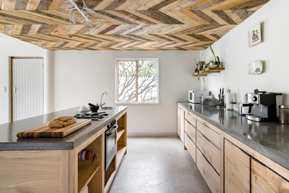 Esempio di una cucina minimal con ante lisce, ante in legno chiaro, top in cemento, paraspruzzi verde, paraspruzzi con lastra di vetro e top grigio