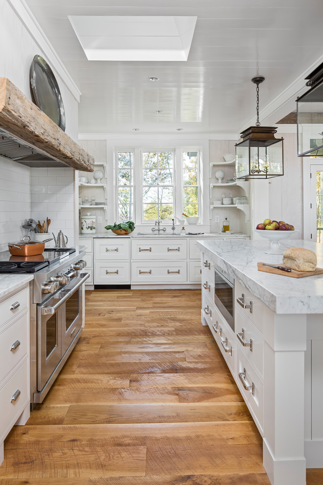 Inspiration for a country kitchen in Other with an undermount sink, shaker cabinets, white cabinets, white splashback, subway tile splashback, stainless steel appliances, with island, white benchtop and medium hardwood floors.
