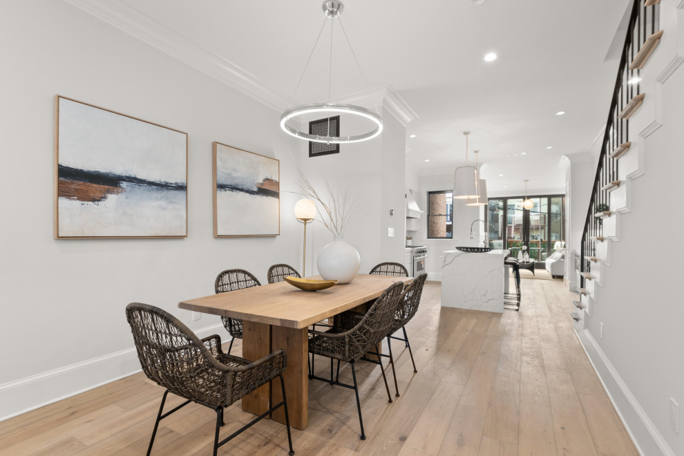 Idee per una sala da pranzo aperta verso la cucina moderna con pareti bianche e parquet chiaro