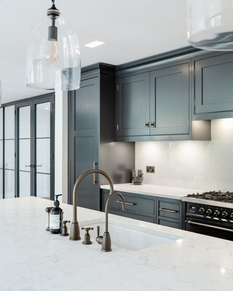 Inspiration for a huge timeless l-shaped open concept kitchen remodel in Hertfordshire with a drop-in sink, shaker cabinets, black cabinets, quartzite countertops, white backsplash, black appliances, an island and white countertops