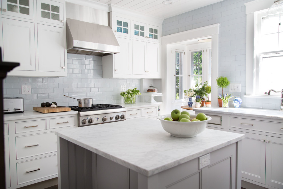 Example of a classic l-shaped dark wood floor kitchen design in New York with an undermount sink, recessed-panel cabinets, white cabinets, white backsplash, subway tile backsplash, stainless steel appliances and an island