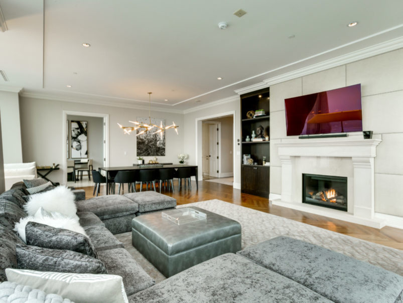This is an example of a large contemporary open concept family room in Toronto with beige walls, medium hardwood floors, a standard fireplace, a stone fireplace surround, a wall-mounted tv and brown floor.