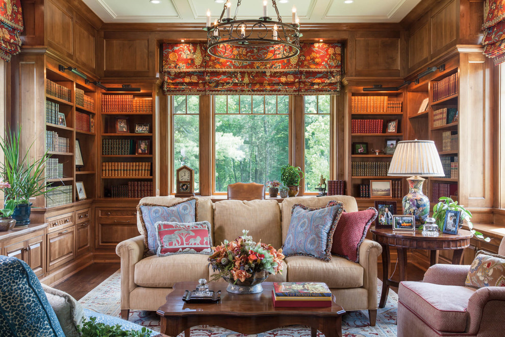 This is an example of a large traditional home office with dark hardwood floors, brown floor and a library.