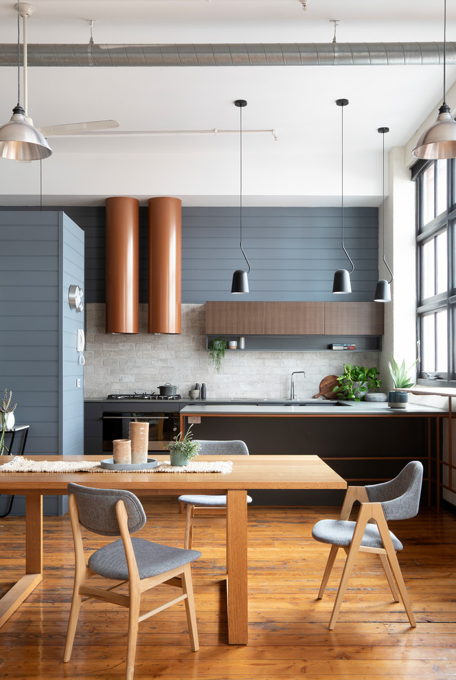 Inspiration for a mid-sized contemporary u-shaped eat-in kitchen in Melbourne with medium hardwood floors, brown floor, a double-bowl sink, flat-panel cabinets, grey cabinets, quartz benchtops, grey splashback, ceramic splashback, stainless steel appliances, with island and grey benchtop.