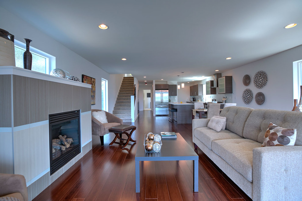 This is an example of a small contemporary open concept living room in Seattle with white walls, bamboo floors, a standard fireplace, a tile fireplace surround and brown floor.