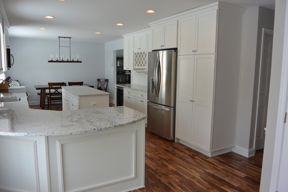 Example of a mid-sized transitional u-shaped medium tone wood floor and brown floor eat-in kitchen design in Baltimore with an undermount sink, recessed-panel cabinets, white cabinets, granite countertops, white backsplash, subway tile backsplash, stainless steel appliances and an island