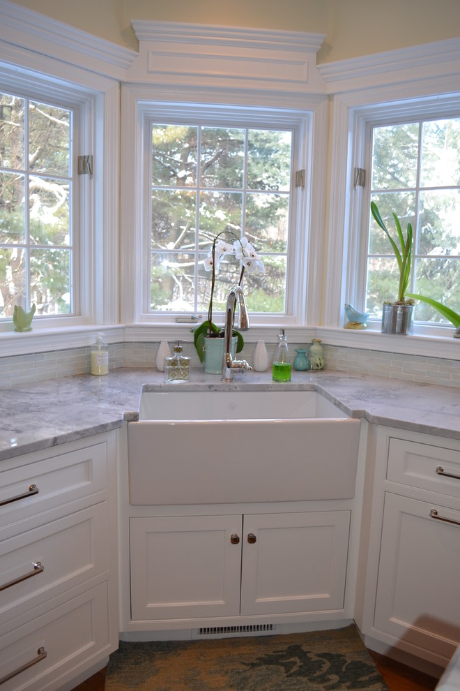 Photo of a large traditional l-shaped eat-in kitchen in Boston with a farmhouse sink, recessed-panel cabinets, white cabinets, granite benchtops, green splashback, glass tile splashback, stainless steel appliances, medium hardwood floors and with island.