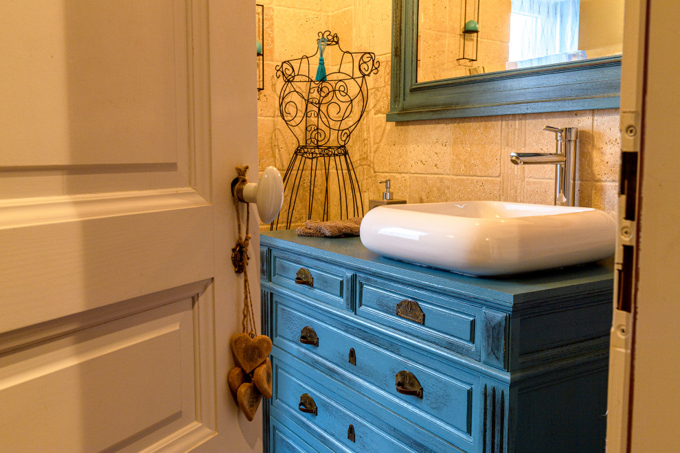 На фото: маленькая ванная комната в стиле неоклассика (современная классика) с раздельным унитазом, бежевой плиткой, плиткой из травертина, бежевыми стенами, полом из ламината, коричневым полом, синей столешницей и тумбой под одну раковину для на участке и в саду