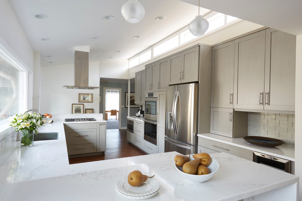 Inspiration for a large transitional u-shaped medium tone wood floor and brown floor eat-in kitchen remodel in Chicago with a single-bowl sink, shaker cabinets, quartz countertops, ceramic backsplash, stainless steel appliances, gray cabinets, white backsplash and a peninsula