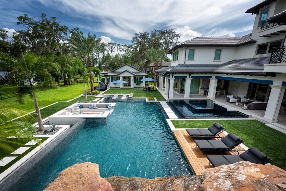 Foto de piscina infinita contemporánea grande a medida en patio trasero con paisajismo de piscina y suelo de baldosas