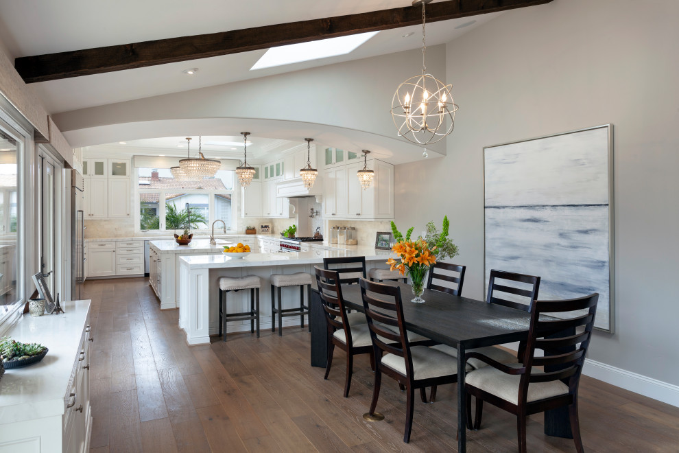 Huge transitional u-shaped medium tone wood floor, brown floor and coffered ceiling eat-in kitchen photo in Santa Barbara with an undermount sink, raised-panel cabinets, white cabinets, marble countertops, white backsplash, marble backsplash, stainless steel appliances, an island and white countertops