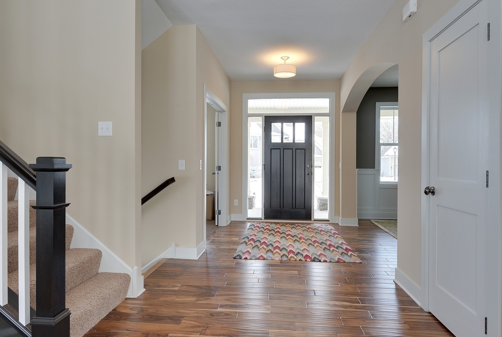 This is an example of a large traditional entry hall in Minneapolis with yellow walls, dark hardwood floors, a single front door and a black front door.