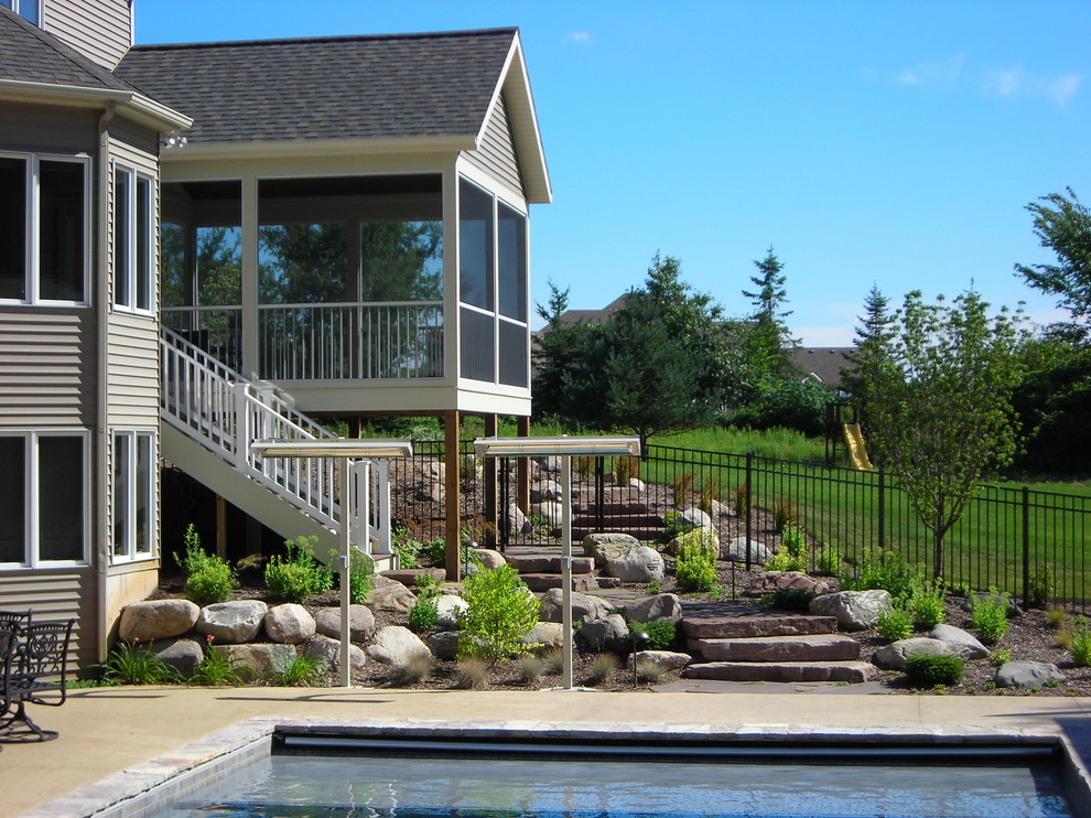 Photo of an expansive traditional backyard custom-shaped natural pool in Grand Rapids with a water feature and natural stone pavers.