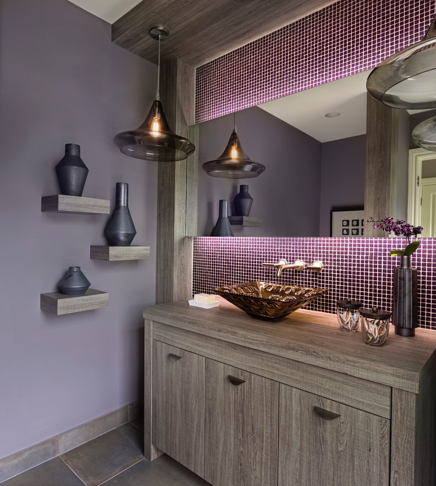 Inspiration for a transitional powder room in Detroit with flat-panel cabinets, mosaic tile, purple walls, a vessel sink, grey floor, brown cabinets, laminate benchtops, brown benchtops and porcelain floors.