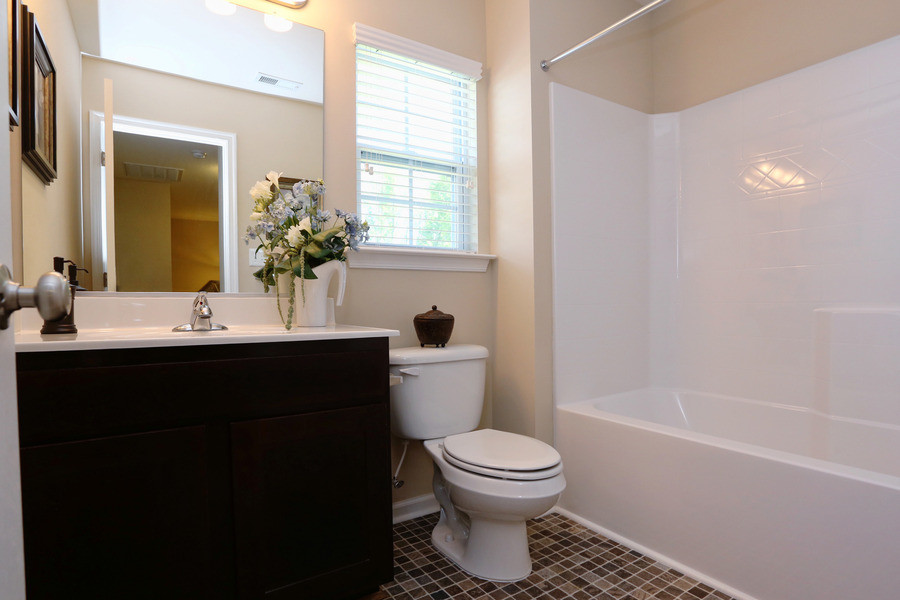 На фото: ванная комната в современном стиле с фасадами с выступающей филенкой, темными деревянными фасадами, душем над ванной, раздельным унитазом, керамической плиткой, бежевыми стенами, полом из винила и врезной раковиной с