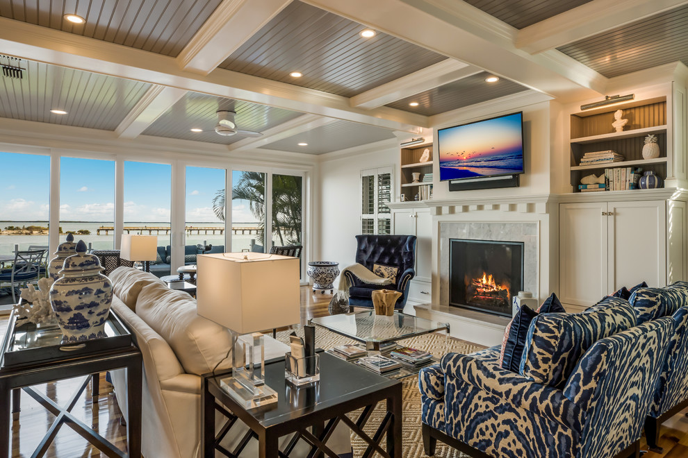 Beach style living room in Miami with white walls, dark hardwood floors, a standard fireplace and brown floor.