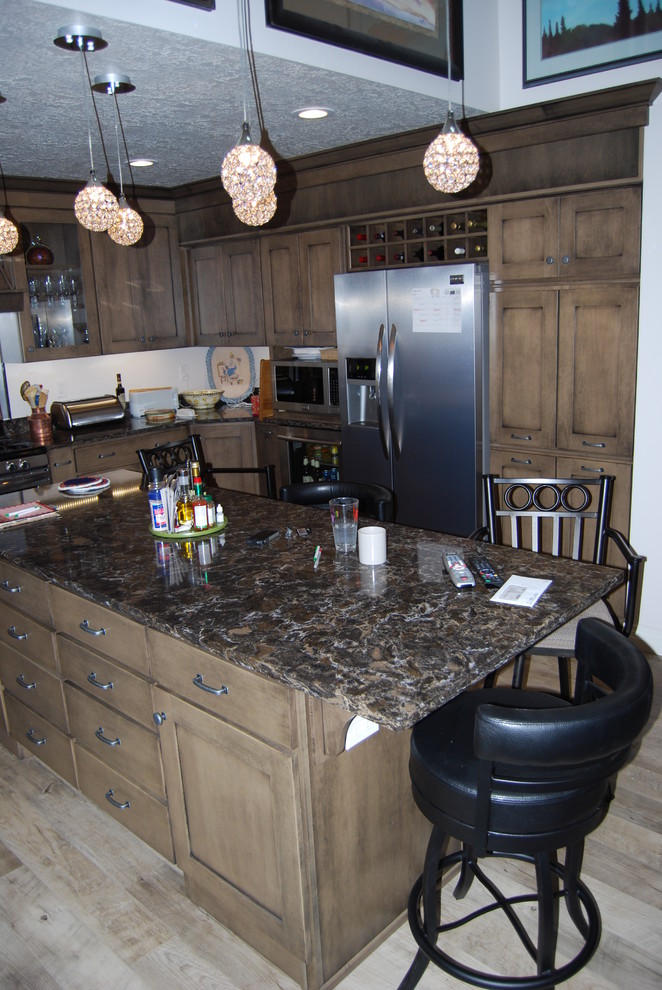 Large transitional u-shaped vinyl floor and brown floor eat-in kitchen photo with recessed-panel cabinets, brown cabinets, black backsplash, stainless steel appliances, an island, quartz countertops and a double-bowl sink