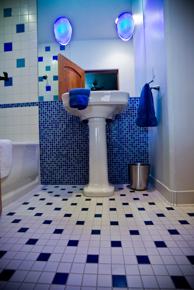 This is an example of a mid-sized eclectic 3/4 bathroom in Albuquerque with an alcove tub, a shower/bathtub combo, blue tile, white tile, mosaic tile, white walls, ceramic floors, a pedestal sink and solid surface benchtops.
