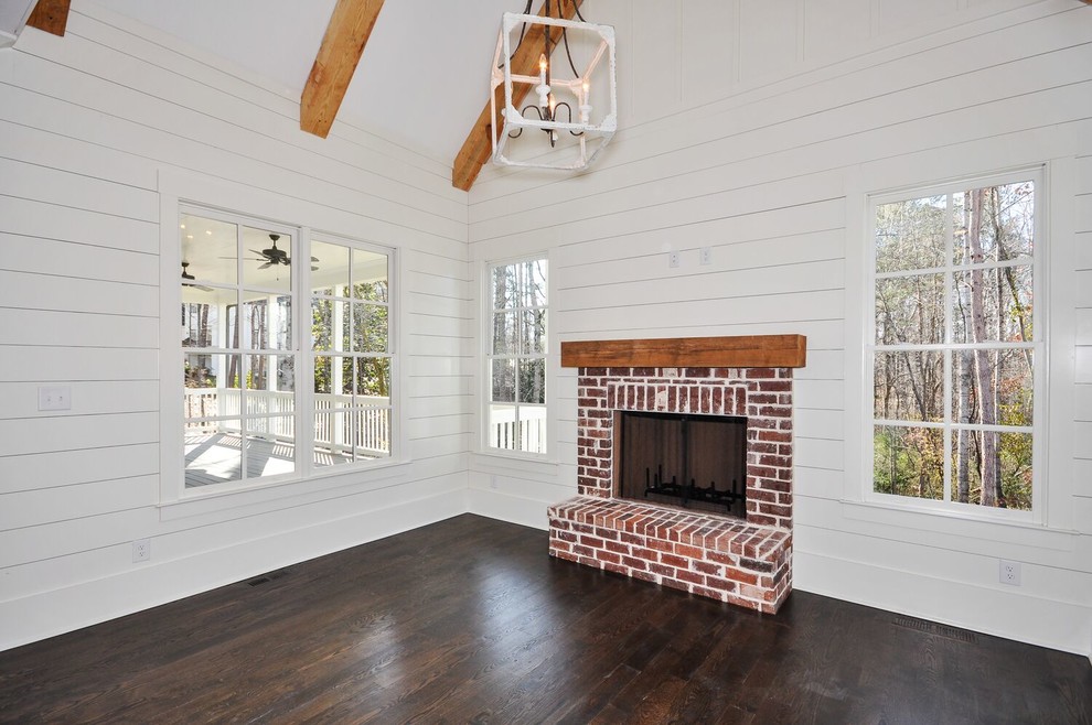 Mid-sized country formal open concept living room in Atlanta with white walls, dark hardwood floors, a standard fireplace, a brick fireplace surround, no tv and brown floor.