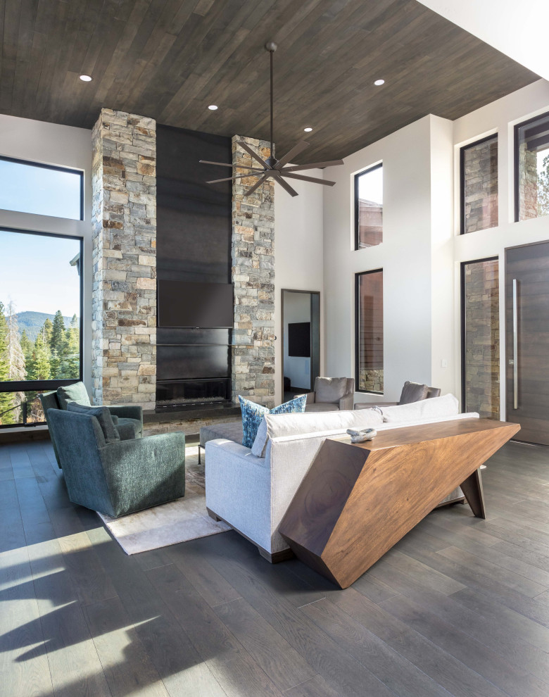 This is an example of a large transitional open concept family room in Sacramento with white walls, a standard fireplace, a stone fireplace surround, a wall-mounted tv, wood, dark hardwood floors and black floor.