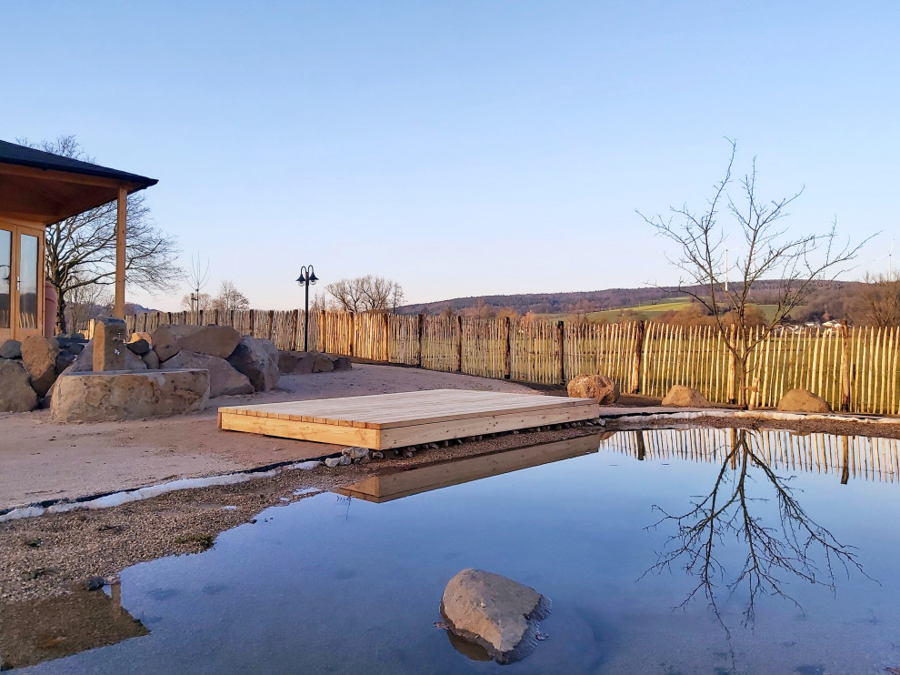 Idee per un grande laghetto da giardino contemporaneo esposto in pieno sole davanti casa in inverno con ghiaia e recinzione in legno
